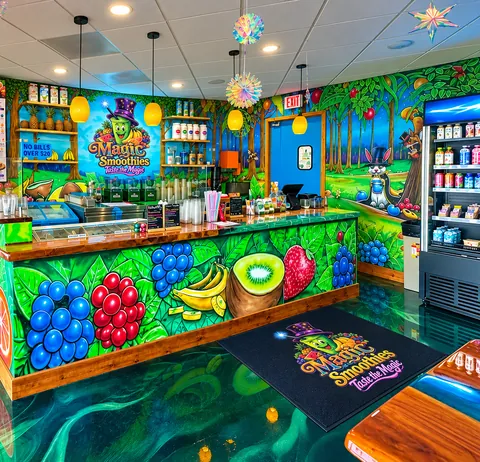 The shop's counter, painted with fruit, under hanging lights, with the Magic Smoothies logo on the mural wall behind it